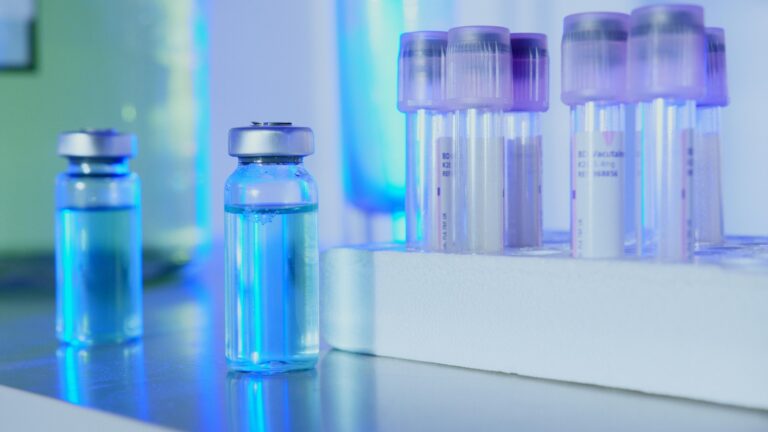 Flacons de laboratoire en verre transparent alignés sur une paillasse stérile pour les chercheurs cherchant un Fournisseur de Peptides Europe fiable.