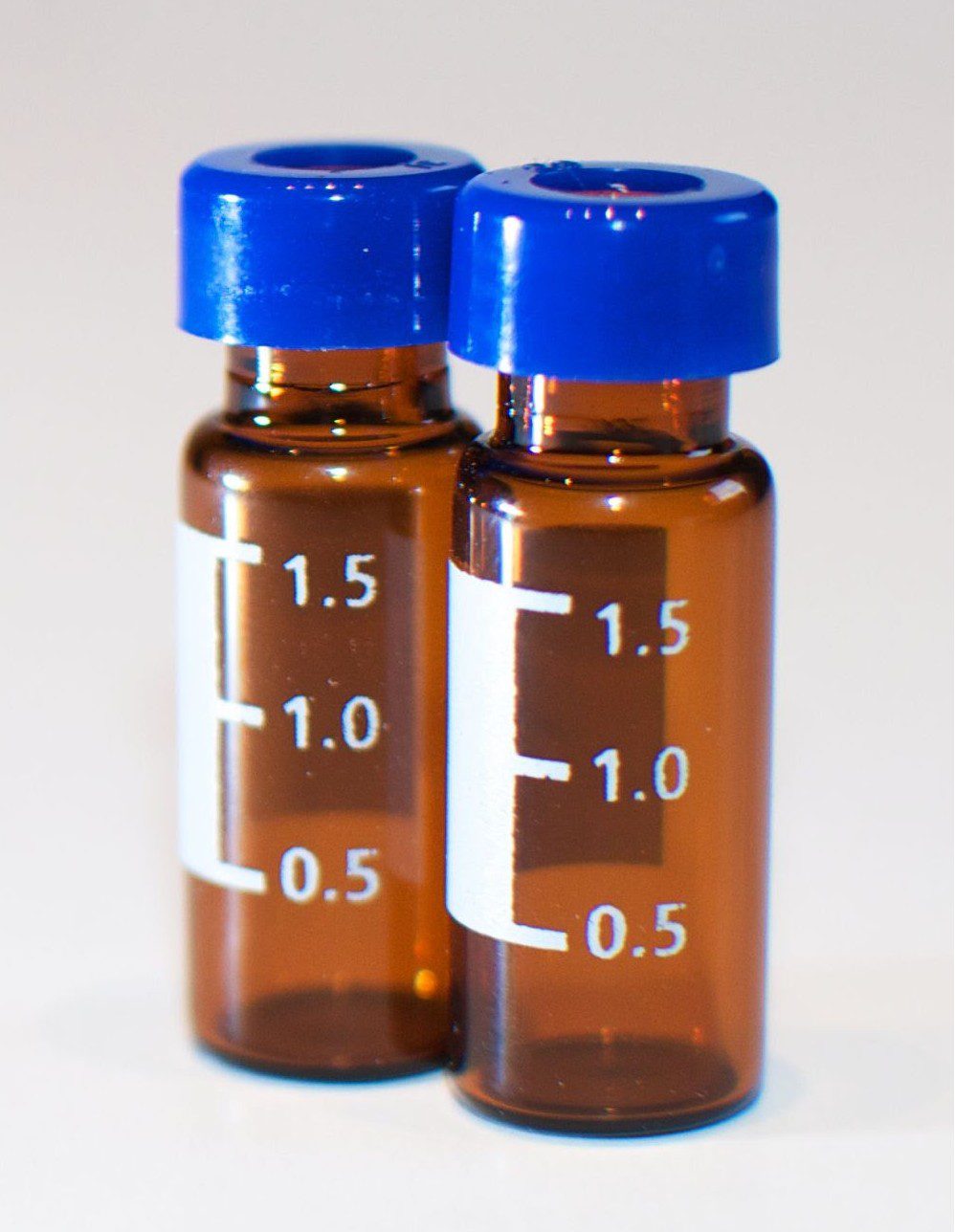 Two amber glass laboratory vials with blue caps on a clean white background for laboratories looking to buy research peptides europe.